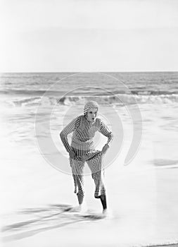 Woman in a striped suit stepping out of the ocean