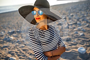 Woman in stripped dress with a hat on the beach