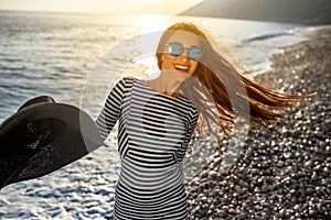 Woman in stripped dress with a hat on the beach