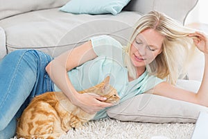 Woman stroking cat while playing with hair on rug