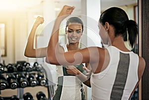 Woman, strong arm and flex in mirror at gym with fitness, workout and exercise of bodybuilder with reflection. Progress