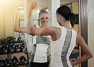 Woman, strong and flex in mirror at gym with fitness, workout and exercise of bodybuilder with reflection. Progress, arm