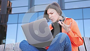 Woman struggling with broken computer and closing it outdoor