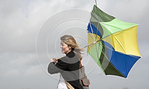 Woman struggling to hold her umbrella on a windy day photo