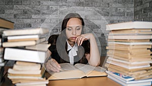 Woman student boring reading book at library with a lot of books in university. Student disheartened reading book for