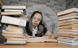 Woman student boring reading book at library with a lot of books in university. Student disheartened reading book for