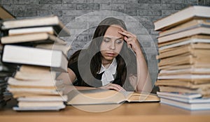 Woman student boring reading book at library with a lot of books in university. Student disheartened reading book for