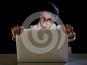 Woman or student girl working on laptop computer late at night holding the screen screaming