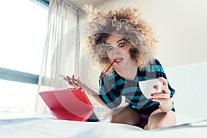 Woman student on her bed learning for exam in panic