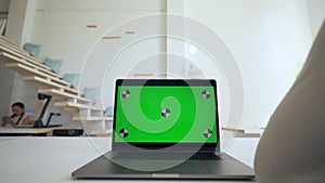 Woman studies online via modern laptop with green screen