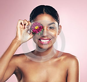 Woman, studio and portrait for natural beauty with flower over eye, cosmetics and smile. Female model, happiness and