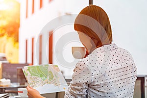 Woman study map drinking coffee in a street cafe. Redhead happy girl travel Canary islands and looking for a new place