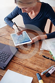 Woman studying at home. Female student writing notes on tablet.