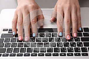 Woman with stylish color nails using laptop, closeup