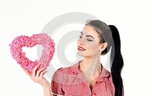 Woman in stylish dress holds symbol of love and smiles.