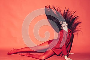 Woman with stylish makeup and long hair posing in total red outfit. Fashion concept. Girl on mysterious face in red