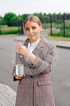 A woman in a stylish suit holds can of small dignity coins. The concept of quits, poverty and begging business ladies