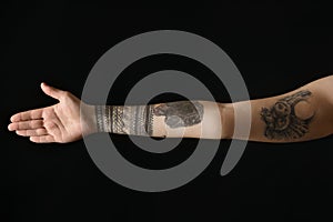 Woman with stylish tattoos on arm against background, closeup