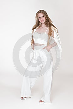 Woman stylishly dressed in white suit jacket, sculpting cupped corset top, trousers and slingbacks photo