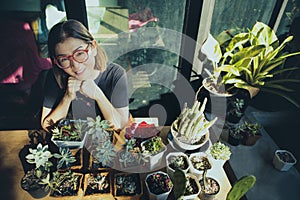 woman and succulent plant in planting pot sitting at greenhouse working table