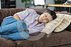 woman suffering from abdominal pain lying on the couch at home Female suffering from severe spasms holding her stomach
