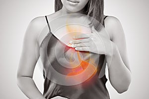 Woman suffering from acid reflux or heartburn against gray background
