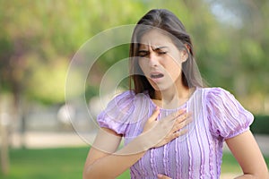 Woman suffering asthma attack in a park