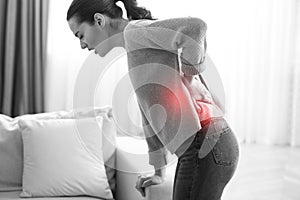 Woman suffering from back pain at home. Bad posture problem