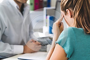 Woman suffering from bad headache or migraine. Appointment with doctor in office room.