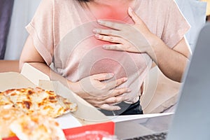 woman suffering from chest pain and heartburn after eating junk food pizza