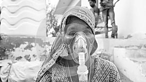 Woman suffering from Covid 19 disease. Old woman admitted in hospital and inhaling emergency oxygen with canula mask photo