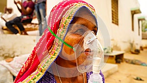 Woman suffering from Covid 19 disease. Old woman admitted in hospital and inhaling emergency oxygen with canula mask photo