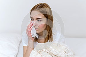 Woman suffering from depression and crying. Young beautiful girl sitting at home and cry wiping away tears with a tissue