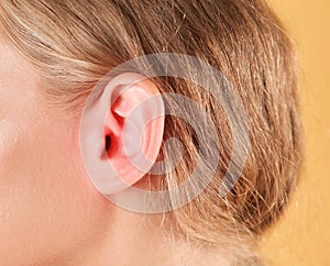 Woman suffering from earache on color background