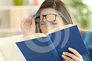 Woman suffering eyestrain reading a book photo