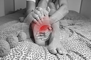 Woman suffering from feet pain or feet ache and massaging painful foot. Leg cramps, pain in legs or muscle spasm