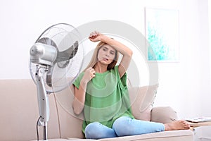 Woman suffering from heat in front of fan