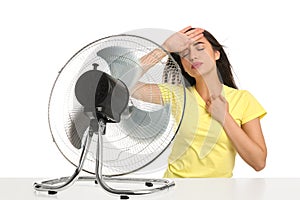 Woman suffering from heat in front of fan on white background. Summer season