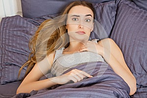 Woman suffering from insomnia or indisposition in bed at home and looking at camera