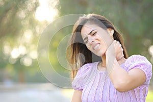 Woman suffering neck ache alone in a park