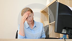 A woman suffering from pain in her head while working on a computer. 4k, slow motion