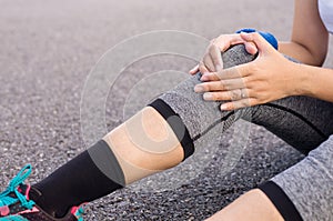 Woman suffering from pain in leg injury hands touching her knee after sport exercise running jogging and workout