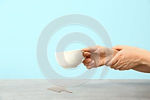 Woman suffering from Parkinson syndrome with cup of coffee against color background