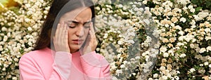 Woman suffering from seasonal pollen allergy near blossoming tree on spring day. Banner design with space for text