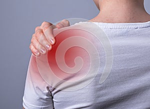 Woman suffering from shoulder pain. Trigger point. Hand holding shoulder with red point closeup. Health problems
