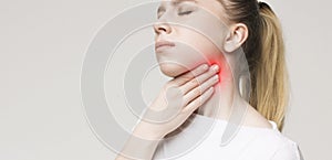 Woman suffering from sore throat, touching her neck