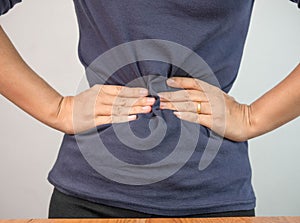 Woman suffering from stomach ache because she has gastritis or menstrual cramps isolated over grey background