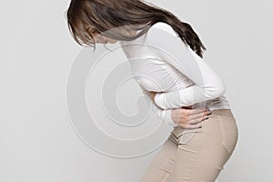 Woman suffering from stomach pain, feeling abdominal pain or cramps, side view. Period menstruation