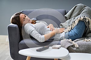 Woman Suffering From Stomachache On Sofa