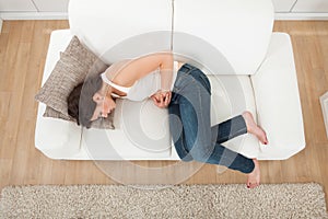 Woman suffering from stomachache on sofa